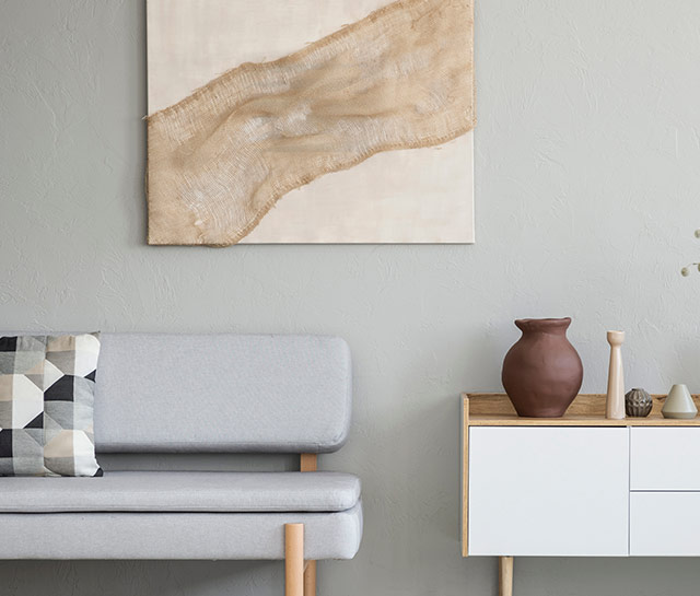 A white couch and table in front of a painting.