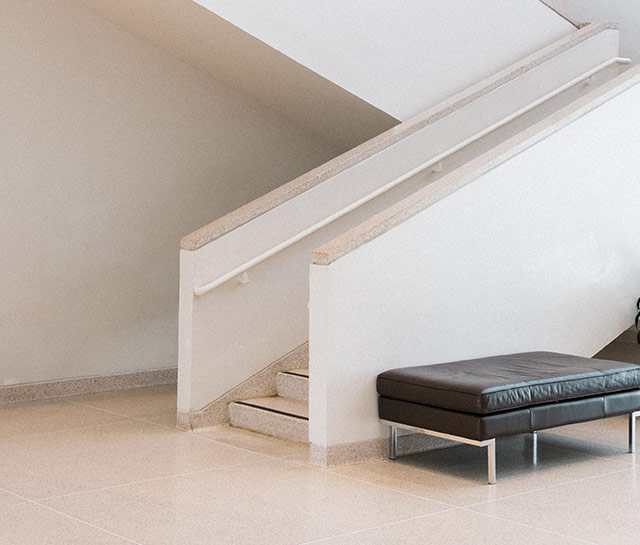 A black leather ottoman sitting in front of stairs.