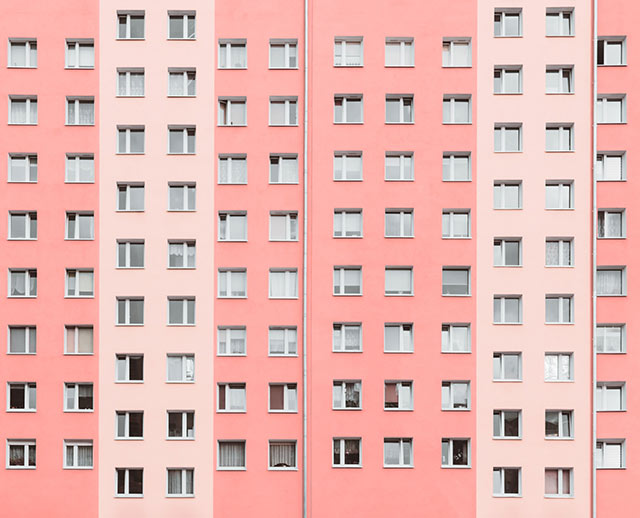 A pink building with many windows and some windows open.