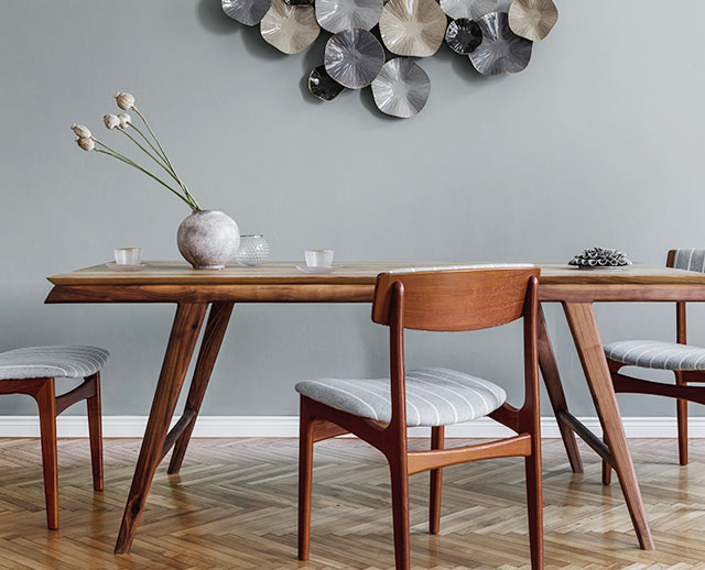 A dining room table with chairs and a vase of flowers.