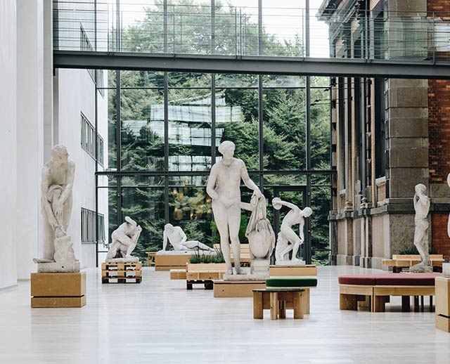 A room filled with statues and benches in front of a window.