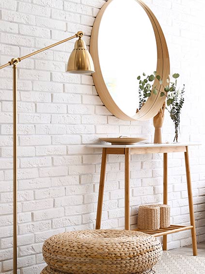 A mirror and table in front of a brick wall.