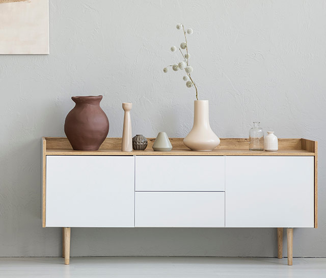 A white sideboard with vases on top of it.