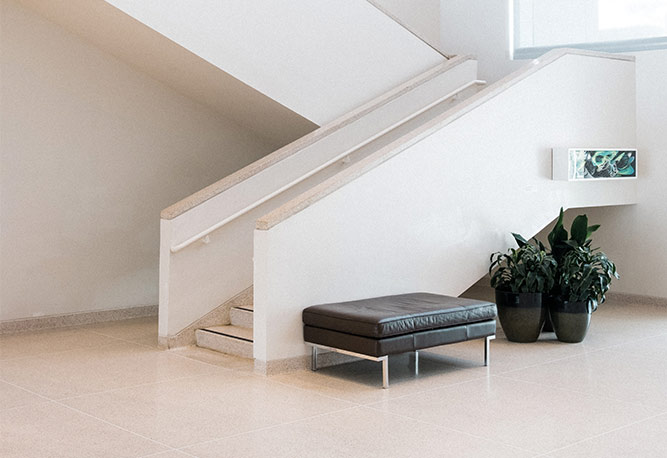 A black ottoman sitting in front of stairs.