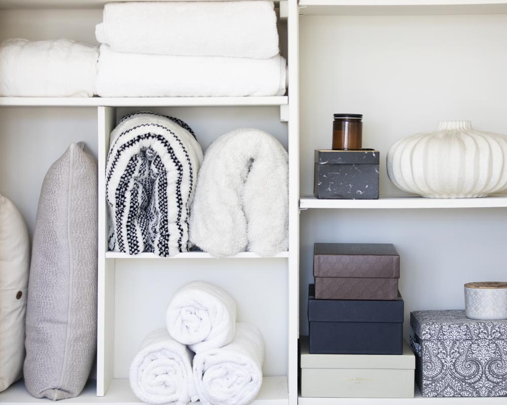 A shelf with many towels and boxes on it