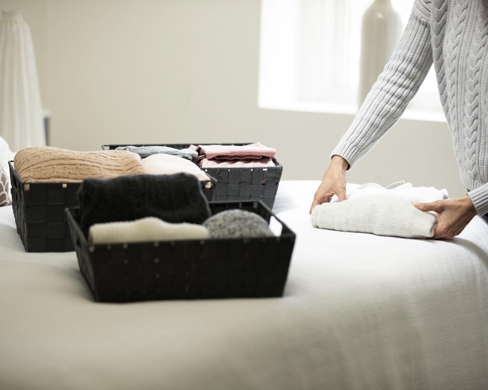 A person is folding towels on top of the bed.